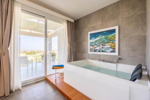 a bathroom with a white tub and a large window at Villa Kalòn Sicily with private pool sea view in Marsala