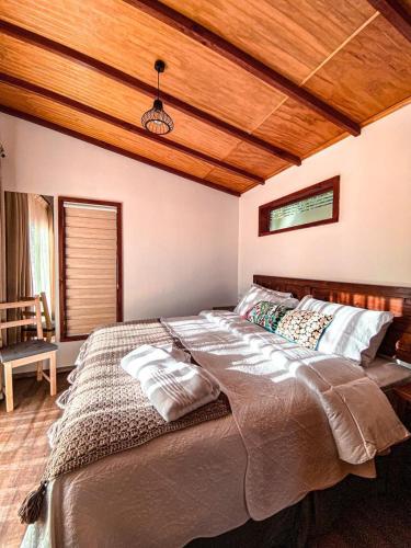 a large bed in a bedroom with a wooden ceiling at Cabañas Boutique Faldeos de La Lajuela in Santa Cruz
