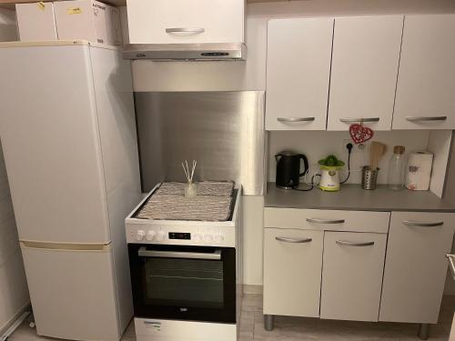 une cuisine avec des armoires blanches et un four à plaques de cuisson dans l'établissement Appartement calme au jardin de Cesar, à Fréjus