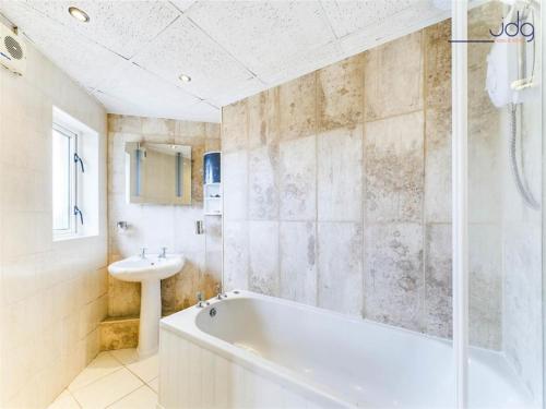 een witte badkamer met een bad en een wastafel bij 1 Buttermere road in Lancaster