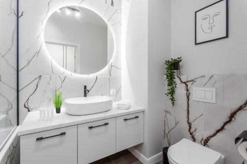 a bathroom with a white sink and a mirror at Warsaw View Prestige Apartment in Warsaw