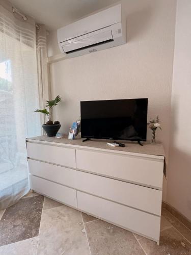 - une télévision au-dessus d'une commode dans la chambre dans l'établissement Logement climatisé à seulement 3 minutes à pied de la mer, au Grau-du-Roi