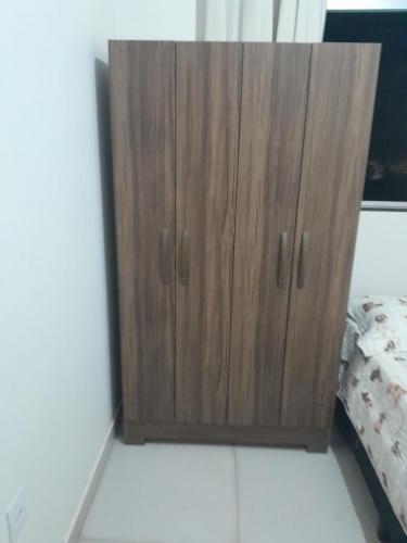 un armario de madera en la esquina de un dormitorio en Quarto próximo Av JK, en Patos de Minas