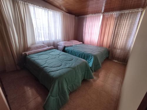 two beds in a small room with windows at Cabaña Turistica Tunwacogua in Nobsa