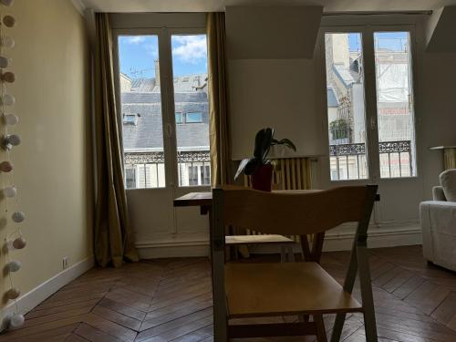 une chambre avec une chaise, une table et des fenêtres dans l'établissement Arc de Triomphe - Champs Elysées - Super emplacement - 5è étage - balcon - 60 m2, à Paris