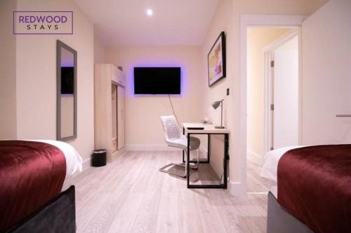 a hotel room with a desk and a tv at Everest Lodge Serviced Apartments for Contractors & Families, FREE WiFi & Netflix by REDWOOD STAYS in Farnborough