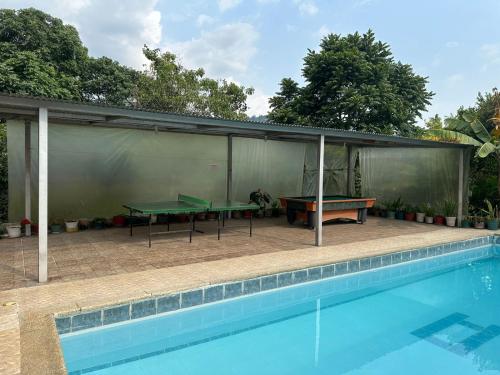 eine Terrasse mit zwei Tischtennisplatten neben einem Pool in der Unterkunft Finca Santa Lucia, Anolaima in Anolaima