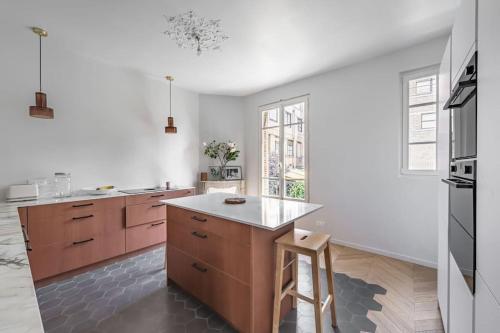 - une cuisine avec des murs blancs, des placards en bois et un comptoir dans l'établissement Très bel appartement sur Vanves, à Vanves