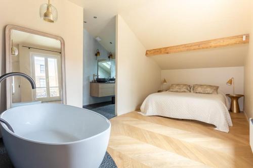 La salle de bains est pourvue d'une baignoire en face d'un lit. dans l'établissement Très bel appartement sur Vanves, à Vanves