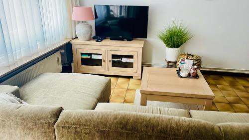 een woonkamer met een bank, een tafel en een tv bij Zeebries in Blankenberge