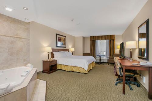a hotel room with a bed and a desk and a tub at Holiday Inn Express Hotel & Suites - Slave Lake, an IHG Hotel in Slave Lake