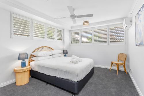 a bedroom with a bed with white walls and windows at Beachfront 2-Bed with Pool, BBQ & Tennis Court in Gold Coast