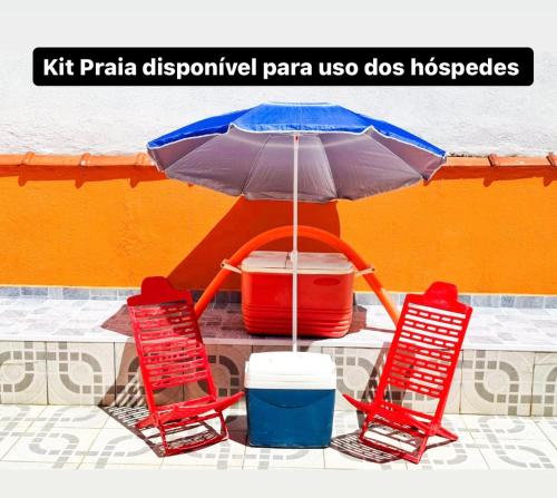 two red chairs and an umbrella and two buckets at No Centro a 3 min da praia, Pet Friendly e Wi Fi in Peruíbe