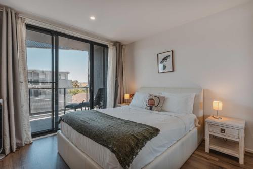 ein Schlafzimmer mit einem großen Bett und einem großen Fenster in der Unterkunft Lonsdale St 1-Bed Unit with Study Area and Parking in Canberra