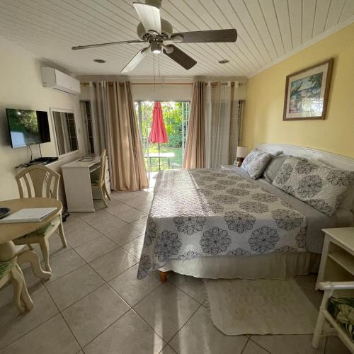 a bedroom with a bed with a ceiling fan at Studio apartment in heart of south coast Barbados in Bridgetown