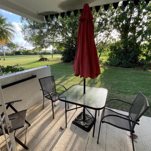una mesa con una sombrilla roja en el patio en Studio apartment in heart of south coast Barbados en Bridgetown