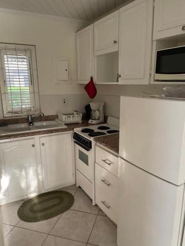a kitchen with white cabinets and a white refrigerator at Studio apartment in heart of south coast Barbados in Bridgetown