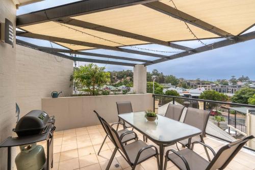 a patio with a table and chairs on a balcony at Mellow in Kiama