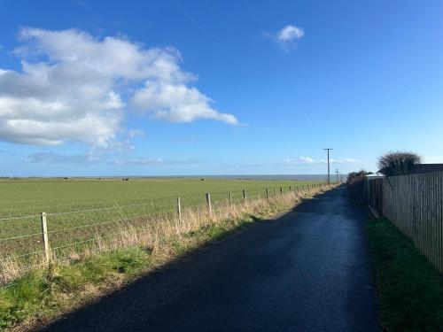 a road with a fence next to a field at Beach House Walk - Crail - Home from Home in Crail