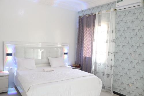 a white bedroom with a white bed and a window at Bel appartement F2 Thies in Thiès