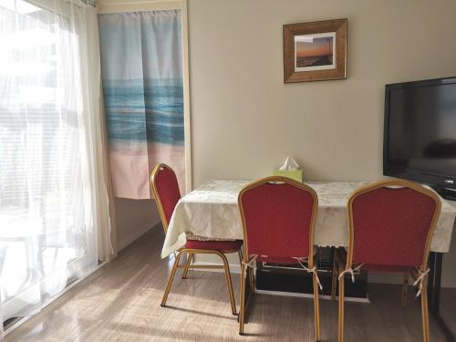 a dining room table with two chairs and a television at Entire guesthouse walking to beach in Rosebud