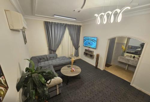 a living room with a couch and a table at استيديو حياة الفيصلية دخول وخدمة ذاتيه in Al Rass