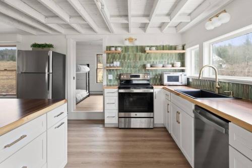 a kitchen with white cabinets and stainless steel appliances at 100% Renovated Stowe Village Farmhouse in Stowe