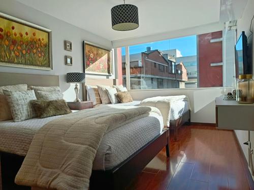 two beds in a bedroom with a large window at CENTRAL Apartment, 3Beds - Balcony - Parking - 6thFLOOR in Quito