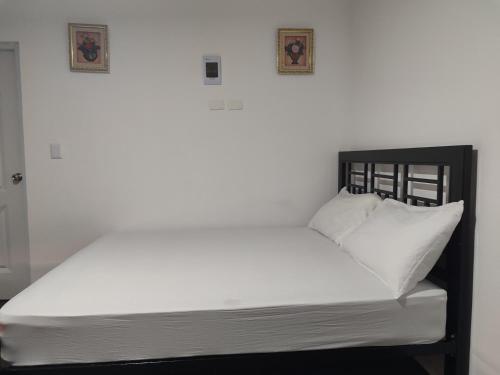 1 cama con sábanas blancas y 2 cuadros en la pared en Aparta Hotel Vista Verde#3, en Santa Bárbara de Samaná