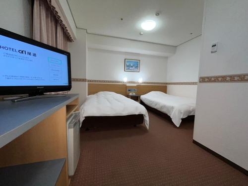 een hotelkamer met 2 bedden en een flatscreen-tv bij Hotel Alpha-One Onomichi in Onomichi