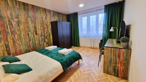 een slaapkamer met een bed en een bureau met een televisie bij Apartament Nepomucen in Przemyśl