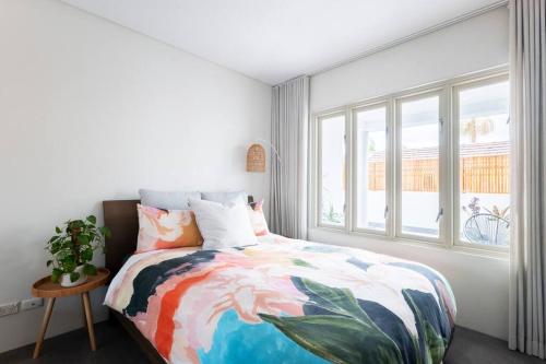 ein Schlafzimmer mit einem Bett mit einer bunten Decke und einem Fenster in der Unterkunft Balmain Designer 1 Bedroom Apartment with Parking in Sydney