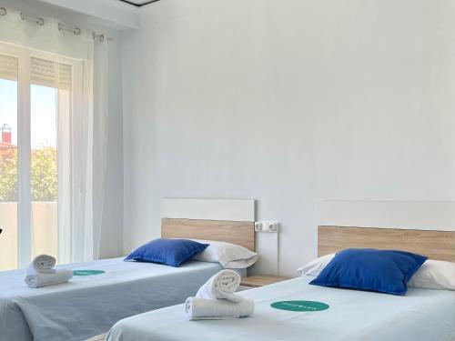 - 2 lits dans une chambre blanche avec des serviettes dans l'établissement Jean XXIII by ARoom - Casa con patio privado, à León