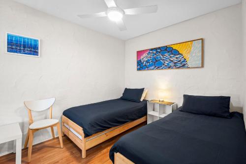 a bedroom with two beds and a table and a chair at La Costa Del Sol in Marcoola