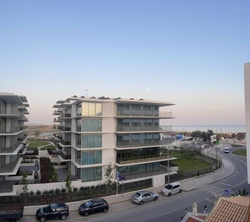 un gran edificio con coches aparcados frente a una carretera en Casa do Leme, en Armação de Pêra