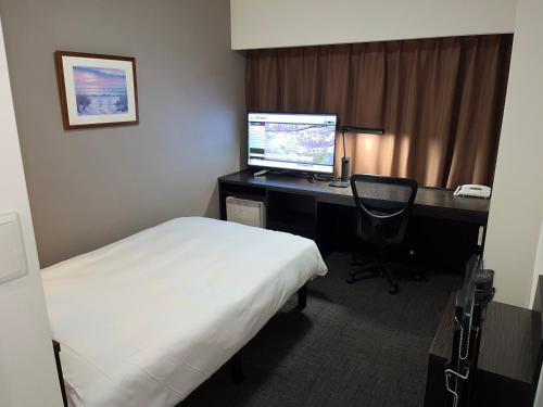 a bedroom with a bed and a desk with a computer at Hotel Alpha-One Himeji Minamiguchi in Himeji