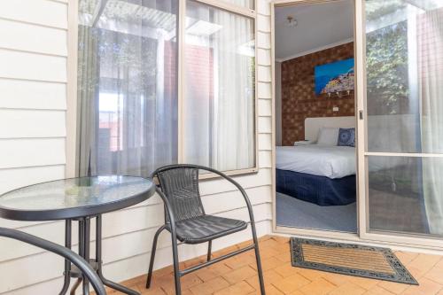 un piccolo balcone con tavolo, sedia e letto di Portarlington Beach Motel a Portarlington