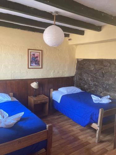 a bedroom with two beds and a stone wall at Samay Wasi Hostel in Cusco