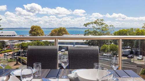 a table with wine glasses and a view of the ocean at Nelson Bay CBD Apartment No 41 Nelson Towers in Nelson Bay