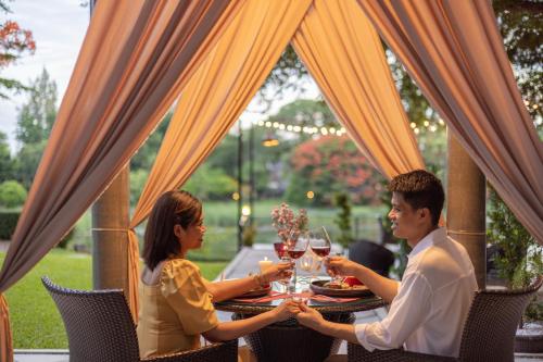a man and woman sitting at a table with wine glasses at U Inchantree Kanchanaburi in Kanchanaburi