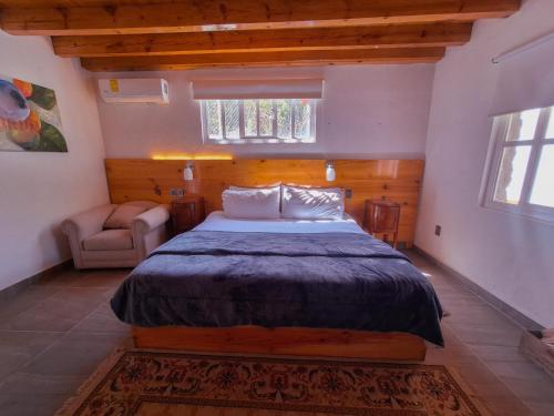 een slaapkamer met een bed en een stoel erin bij Finca la concordia: Hotel frutos del bosque in Zacatlán