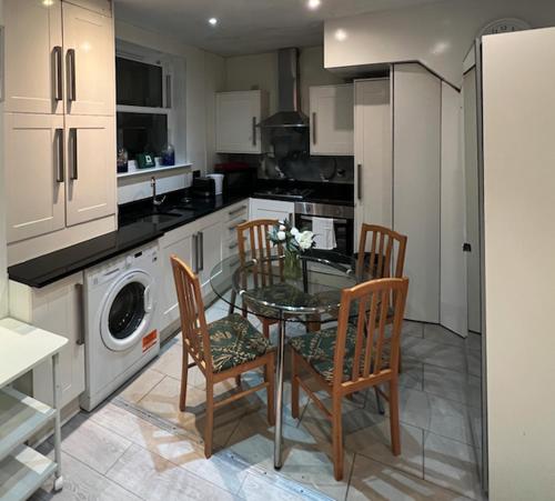 a kitchen with a table and chairs and a kitchen with a dishwasher at London Central Budget Rooms in London