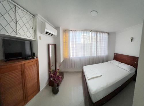 Dormitorio pequeño con cama y TV en Encantador apto en el Rodadero frente a la playa, en Santa Marta