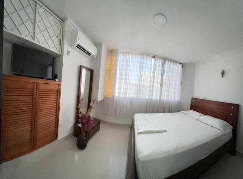 1 dormitorio con 1 cama, TV y ventana en Encantador apto en el Rodadero frente a la playa, en Santa Marta