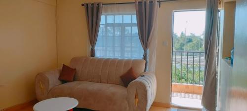 a living room with a couch and a large window at Fancy One Bedroom Juja in Juja