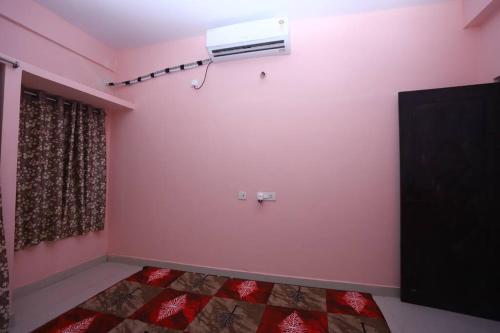 Habitación con una pared de color rosa y aire acondicionado. en Lalitha Residency, en Secunderābād