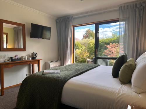 a hotel room with a bed and a large window at Wanaka Springs Lodge in Wanaka