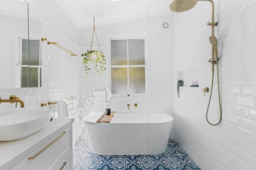 a white bathroom with a tub and a sink at Tranquil 2-Bed Family Home with Deck Among Trees in Brisbane