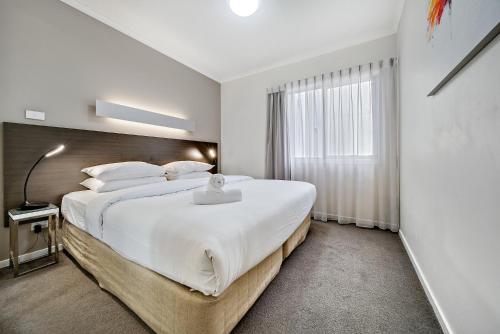 Un dormitorio con una gran cama blanca y una ventana en Comfy 2-Bed Near the Lake with Secure Parking, en Tuggeranong