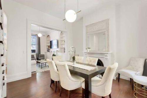 a dining room with a table and white chairs at Chic Large 4 Bedroom Barangaroo The Rocks Sydney in Sydney
